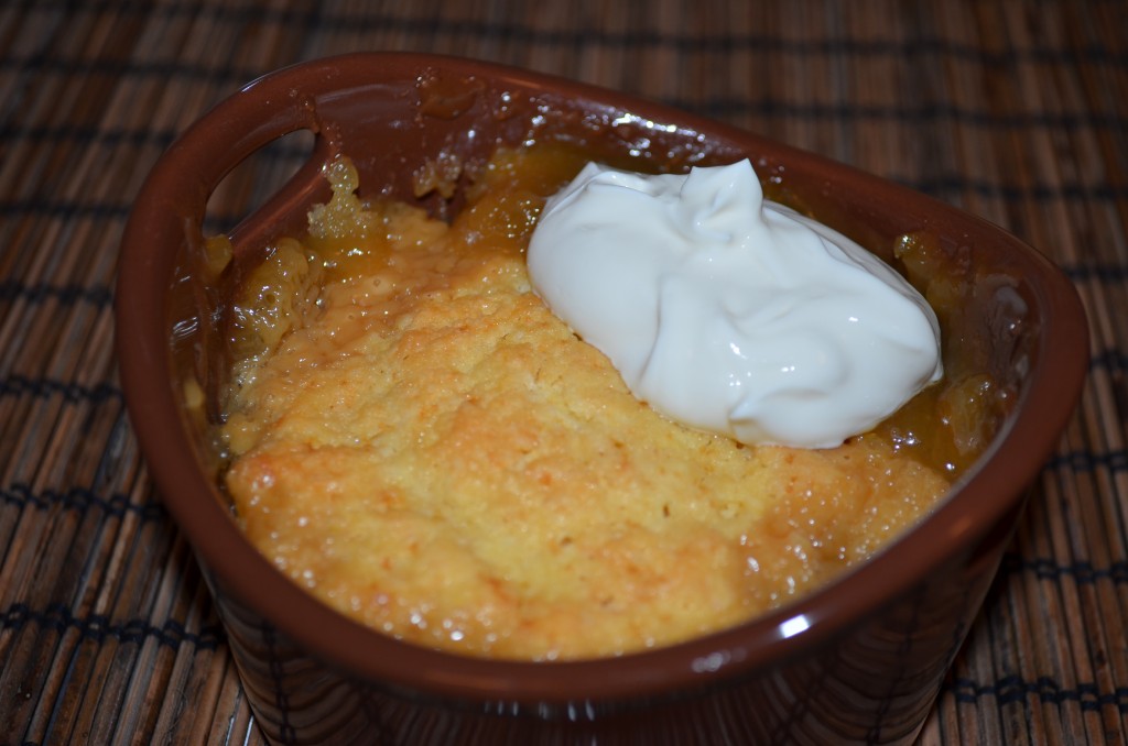 Close up shot of baked pudding in brown ramekin with dollop of sour cream