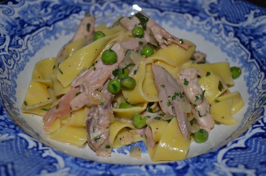pappardelle noodles with shredded turkey and green peas in a blue and white bowl