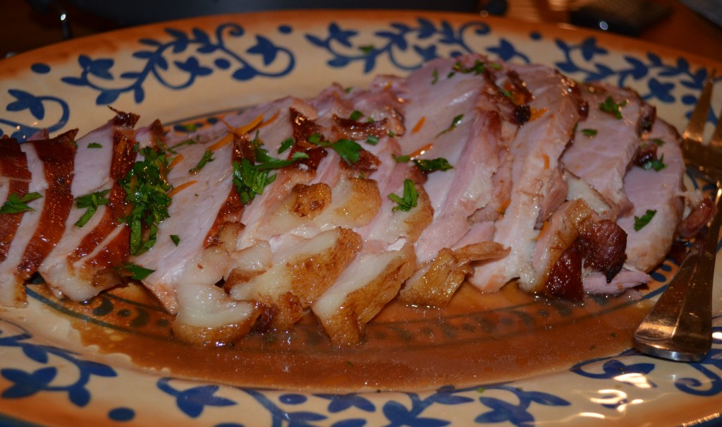 slices of ham on a platter with parsley on top and jus on the platter