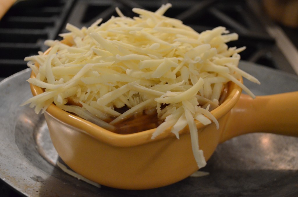 a yellow soup crock with a lot of grated cheese on top