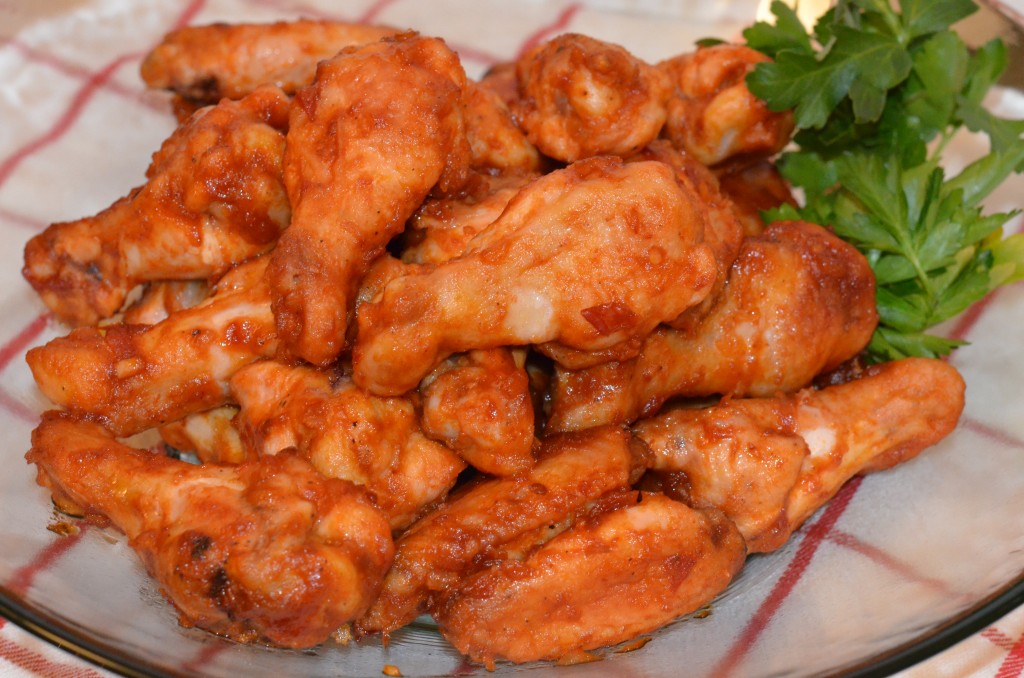 Glass bowl of BBQ chicken wings on red and white tea towel