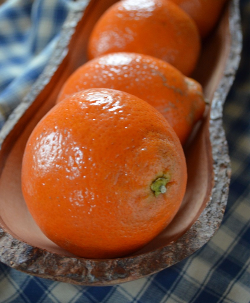 a row of Honeybells in an oval wooden bowl on a blue and cream checked cloth