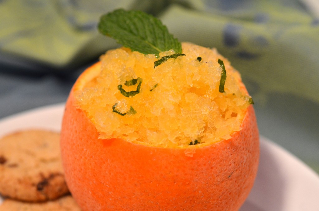 honeybell granita in a hollowed out honeybell peel on a white plate with two cookies on the side