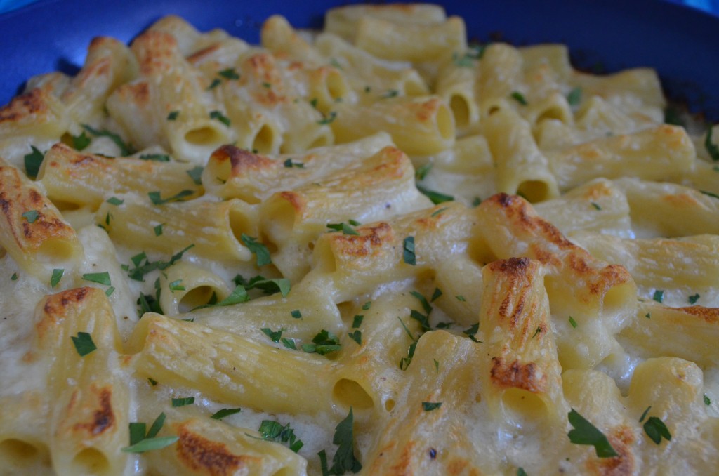 Baked rigatoni with brown edges and parsley sprinkled on top