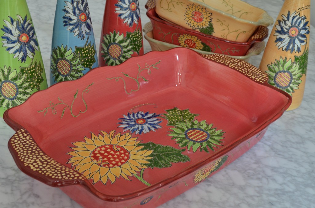 a large red ceramic baker with sunflower design, three smaller dishes in red and cream, four cruets in green, blue, red and cream