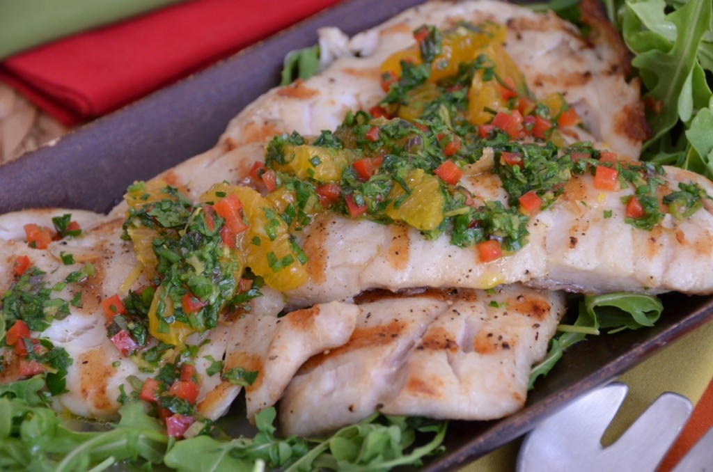 a piece of grilled Pacific Rockfish with colorful salsa - orange segments, red pepper, herbs - on top