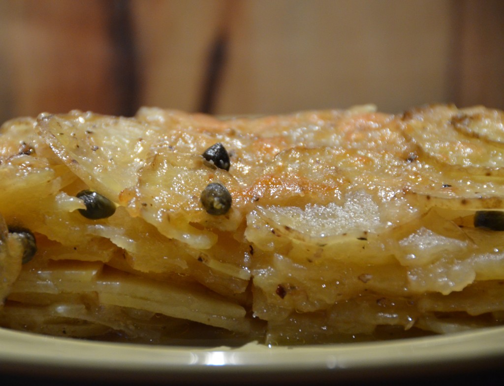 Close up shot of the cross section of a potato gratin. Capers visible