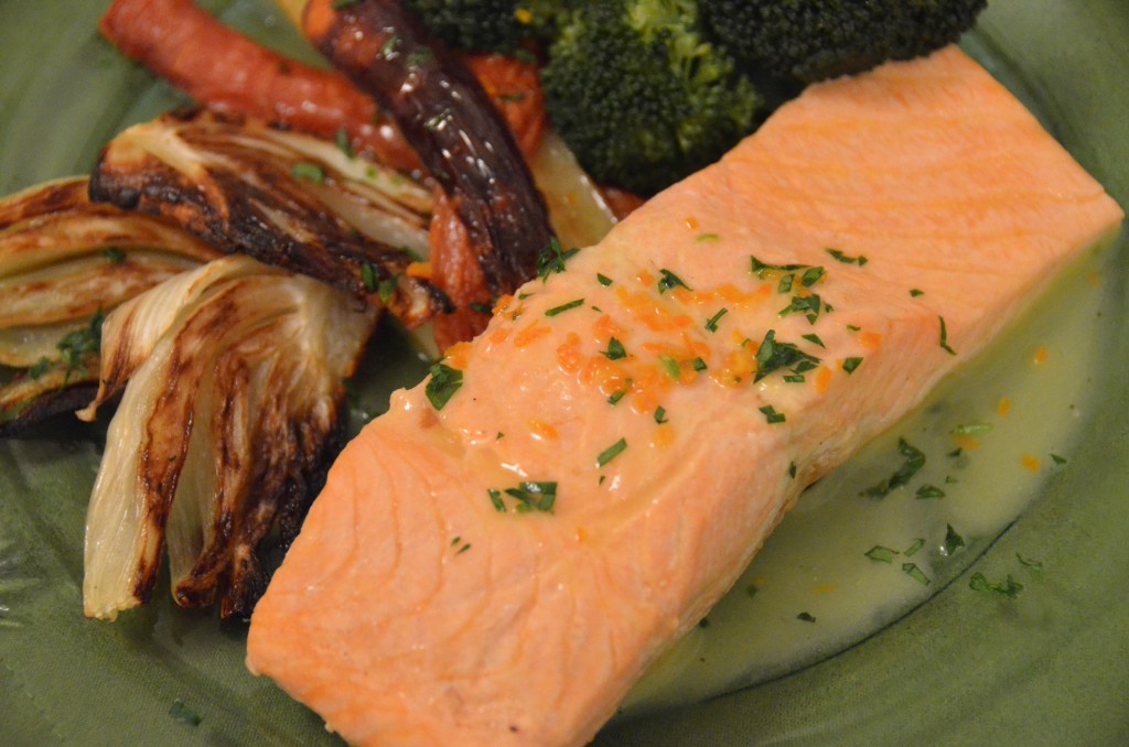 Steelhead trout with melted butter, honey bell zest and parsley on top. Roasted fennel and carrots and broccoli in the background.