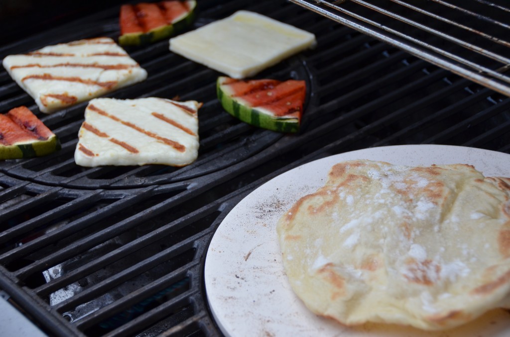 Shot of Griddle bread on pizza stone in foreground and cheese and watermelon grilling in background